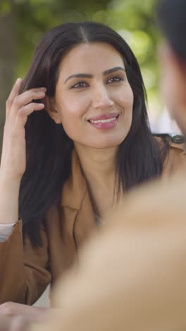 Vertical-Video-Close-Up-Of-Muslim-Couple-On-Date-Meeting-And-Talking-At-Table-On-City-Street-Together-2